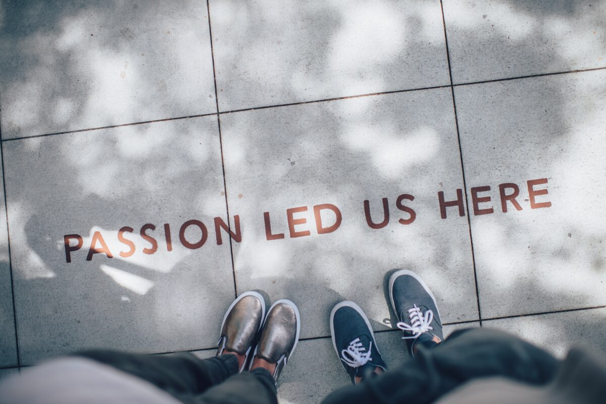 Les pieds s'arrêtent devant les mots "la passion nous a conduits ici" écrits en lettres de laiton sur le trottoir.