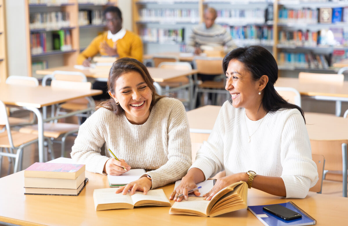 Deux jeunes femmes adultes dans une bibliothèque, lisant des livres et prenant des notes