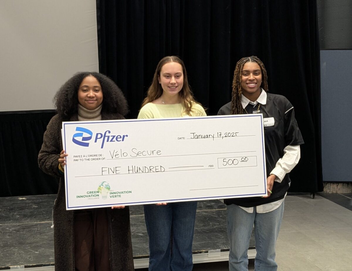 three students holding a large poster of a cheque of $500 in prize money