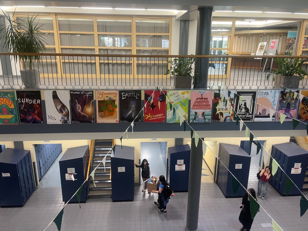 vue de l'atrium inférieur depuis l'atrium supérieur montrant des étudiants en train de ranger leurs casiers sous des affiches présentant les projets de fin d'année