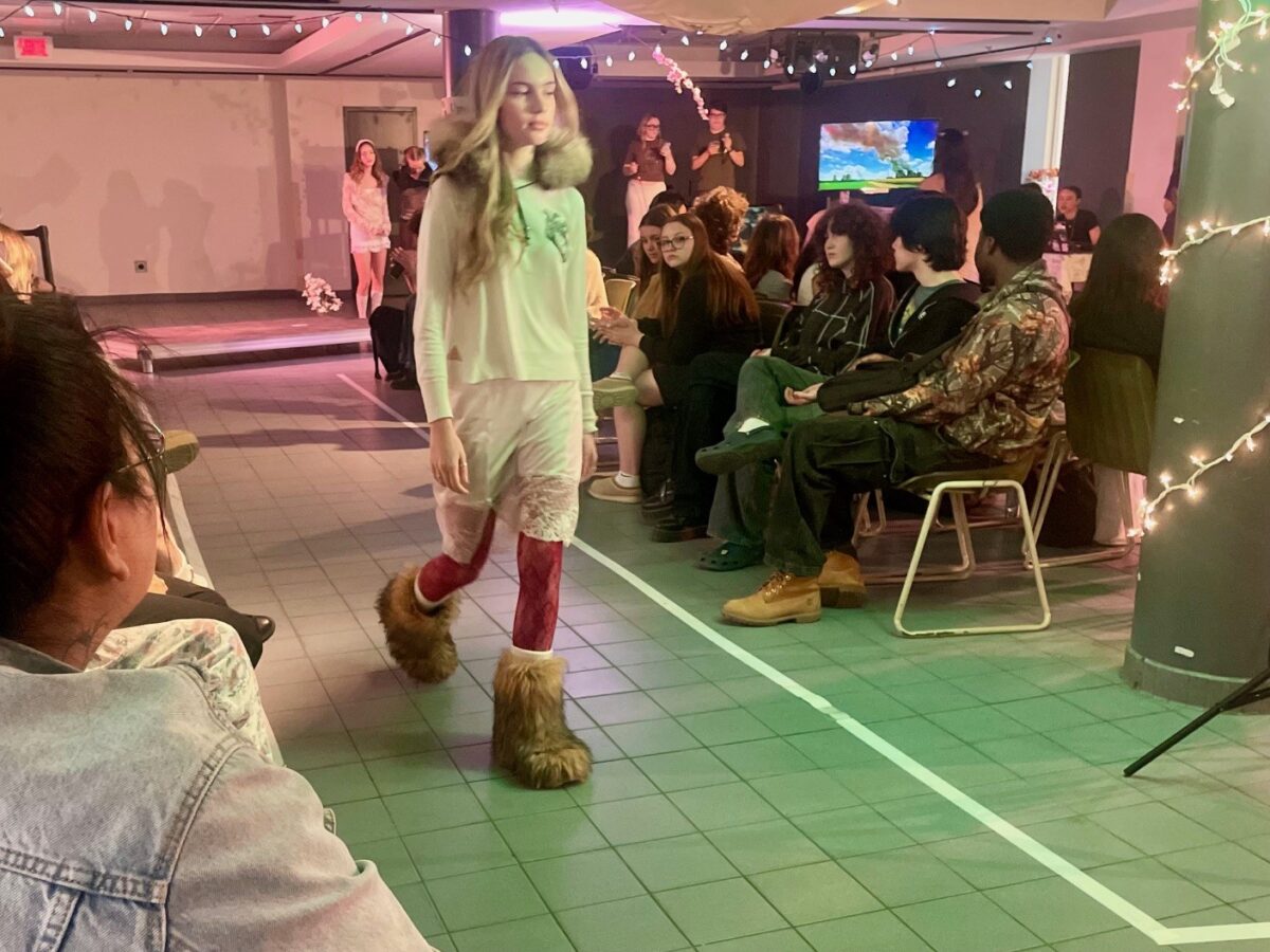 une étudiante mannequin déambulant sur un podium en portant des vêtements recyclés