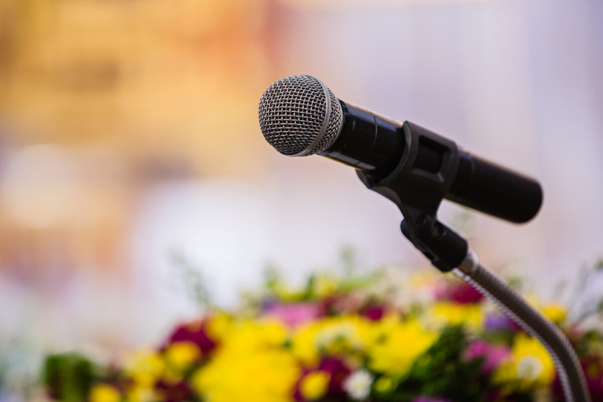 un microphone et des fleurs au premier plan avec un arrière-plan flou