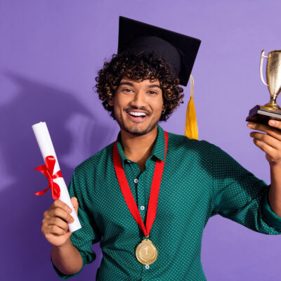 étudiant portant la casquette de fin d'études et tenant un certificat et un trophée