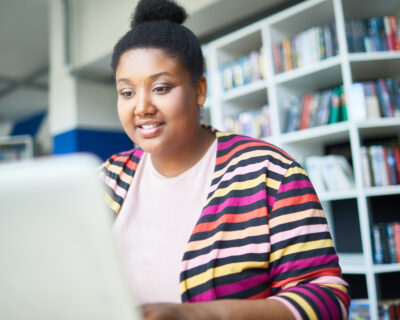 Cheerful African student reading online article