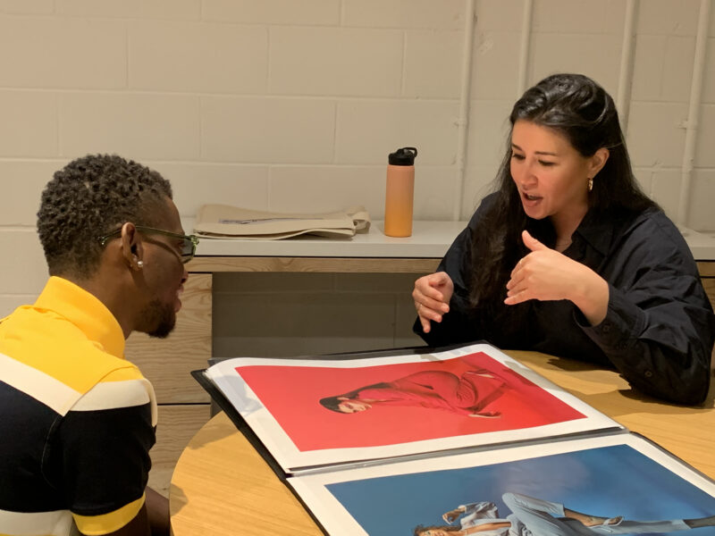 Two individuals sitting at a table looking at poster.