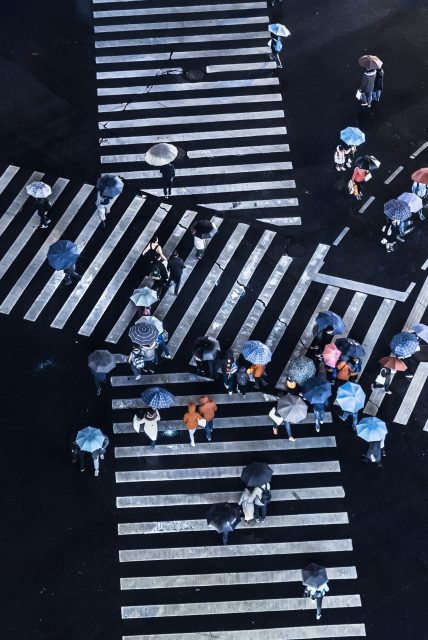 Personnes avec des parapluies traversant une rue