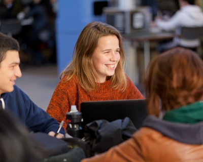 Une étudiante assise à une table de l’atrium.